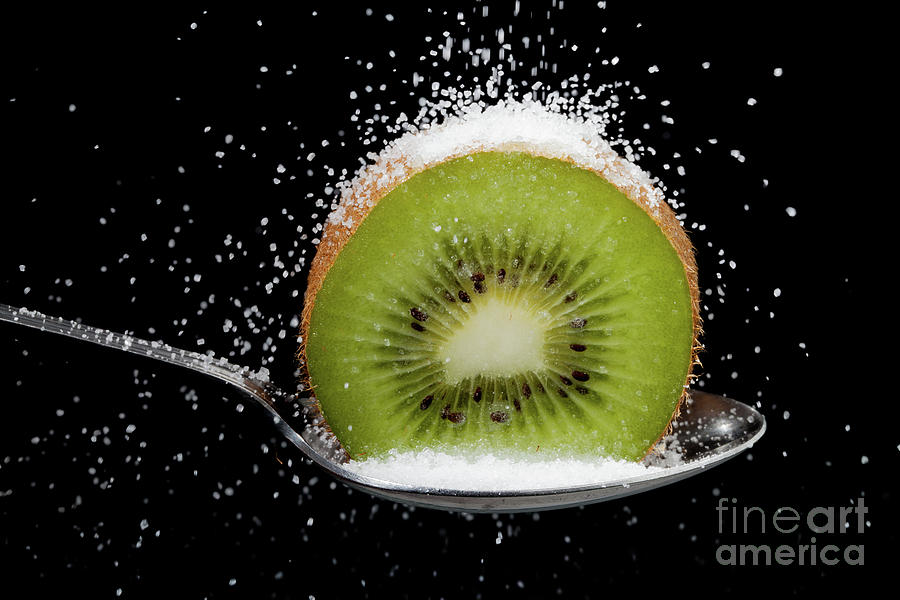 Kiwi fruit cut in half on a spoon with sugar Photograph by Simon Bratt