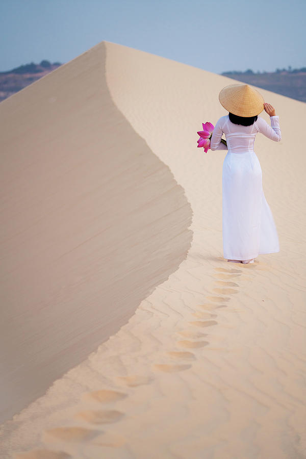 Lady and  lotus flower on hand walk on the sand in Mui ne desert Photograph by Anek Suwannaphoom
