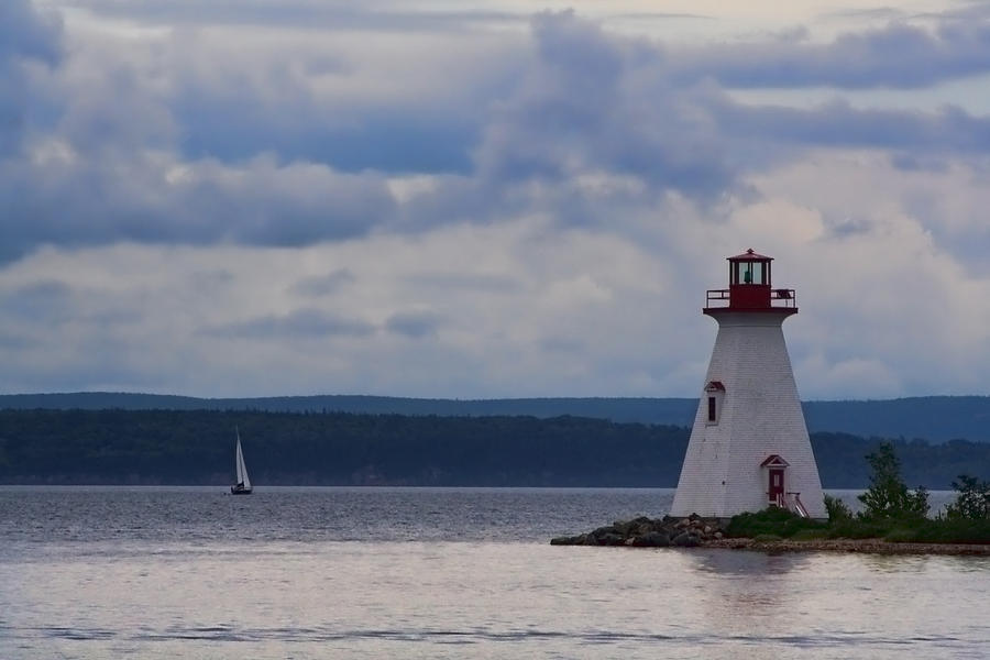 Lighthouse and a sail boat in Nova Scotia Photograph by Sven Brogren