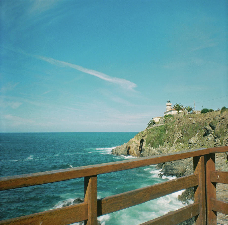 Lighthouse Photograph - Lighthouse over the ocean by Nacho Vega