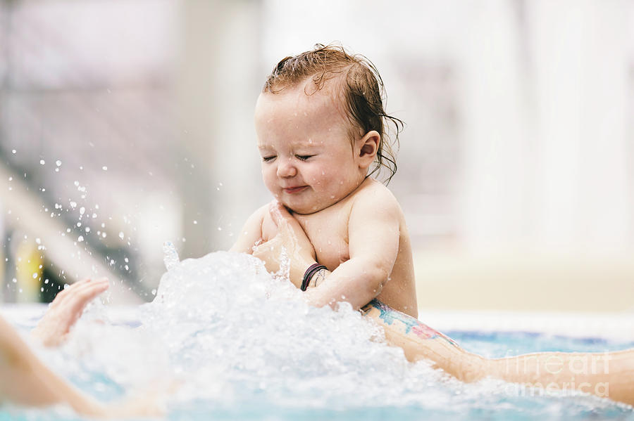 Little baby girl splashing in the water. Photograph by Michal Bednarek