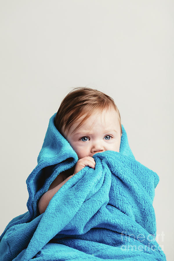 Little baby girl tucked in a cozy blue blanket. Photograph by Michal Bednarek