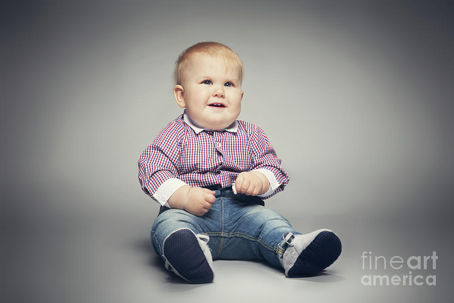 Little child sitting on the floor, smiling. Photograph by Michal Bednarek