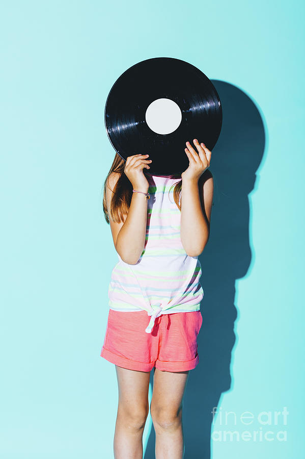 Little girl holding a vinyl disc against her head. Photograph by Michal Bednarek