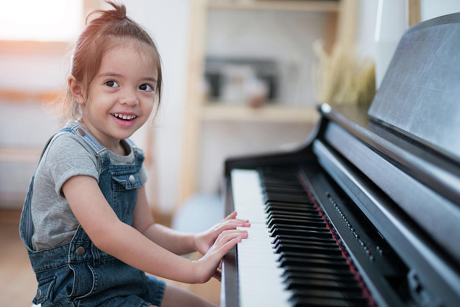 Little girl play piano and sing a song in living room Photograph by Anek Suwannaphoom