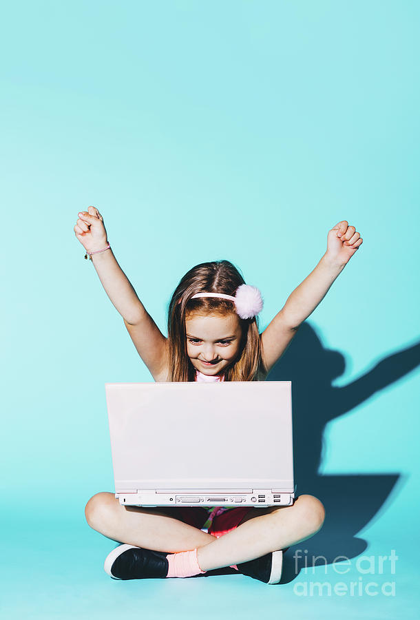 Little girl playing on a pink laptop, raising her hands up Photograph by Michal Bednarek