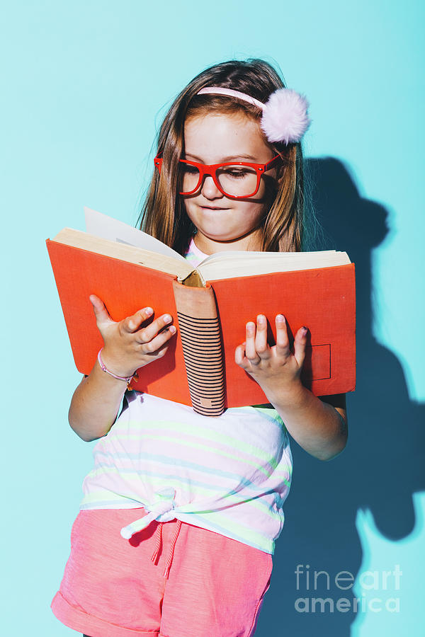 Little girl reading a book, wearing funny red glasses. Photograph by Michal Bednarek