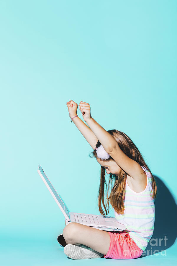 Little girl with laptop on her knees, raising her hands up Photograph by Michal Bednarek