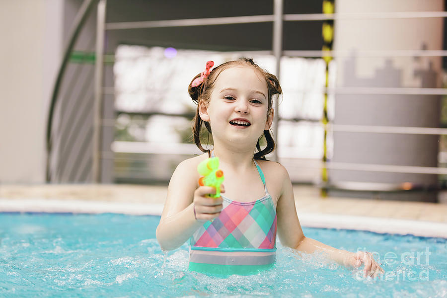 Little girl with water pistol in a swimming pool. Photograph by Michal Bednarek