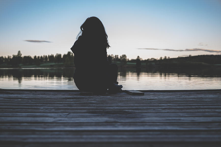 Lone woman resting in a quiet lake scenery Photograph by Aldona Pivoriene