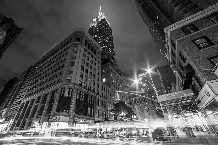 Looking up at the Empire State building from Fifth Avenue at night New York NY Black and White Photograph by Toby McGuire