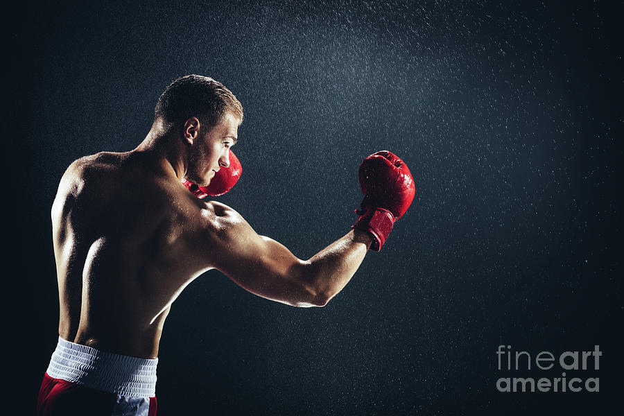 Man boxing with red gloves on his hands in the rain. Photograph by Michal Bednarek