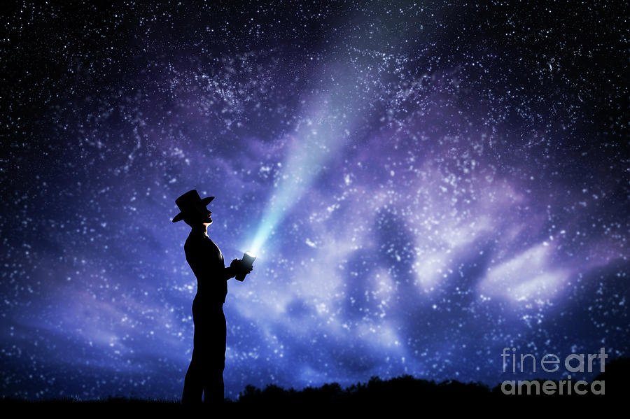Man in hat throwing light beam up the night sky full of stars. To explore, dream, magic. Photograph by Michal Bednarek