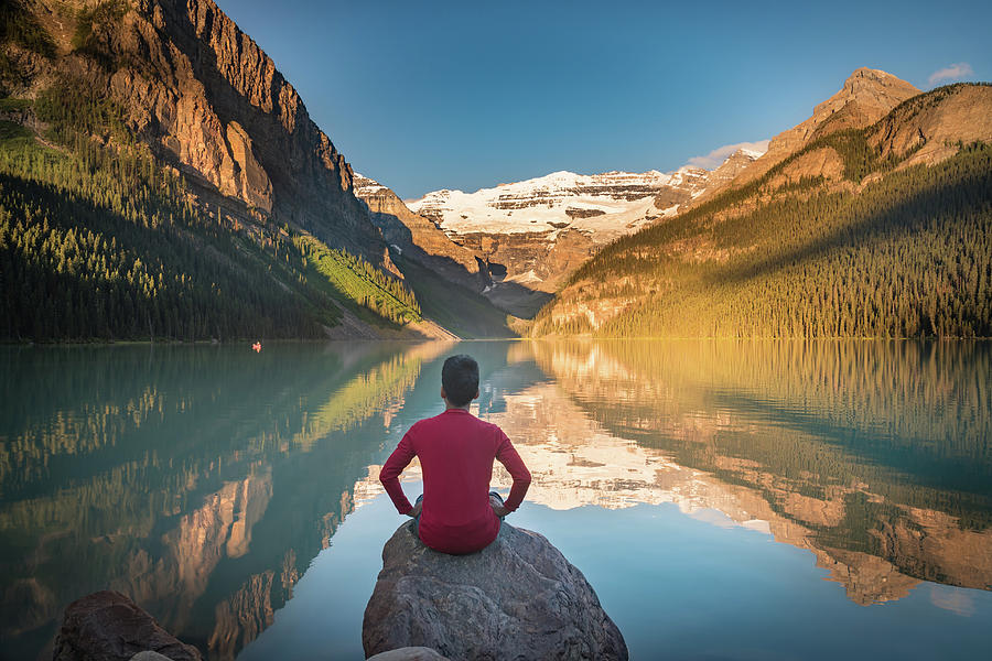 Man sit on rock watching Lake Louise reflections Photograph by William Lee