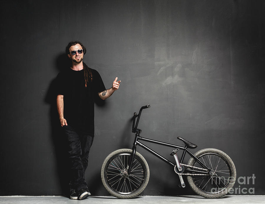Man standing next to his BMX bike, pointing his finger. Photograph by Michal Bednarek