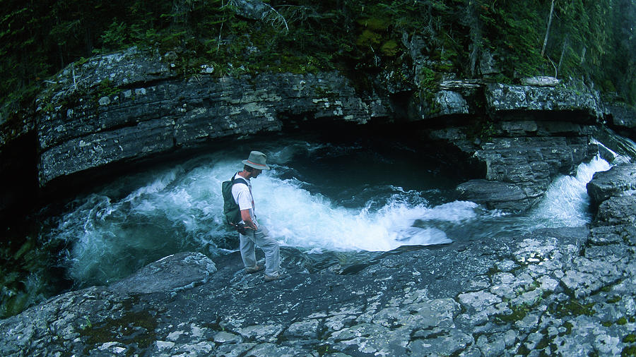 Man Standing Over A High Fast Moving Mountain Stream Photograph