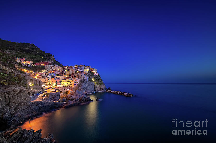 Manarola Photograph - Manarola village during blue hour at night by IPics Photography Manarola Photograph - Manarola village during blue hour at night by IPics Photography
