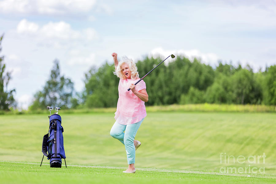 Mature woman jumping with success on a golf course. Photograph by Michal Bednarek