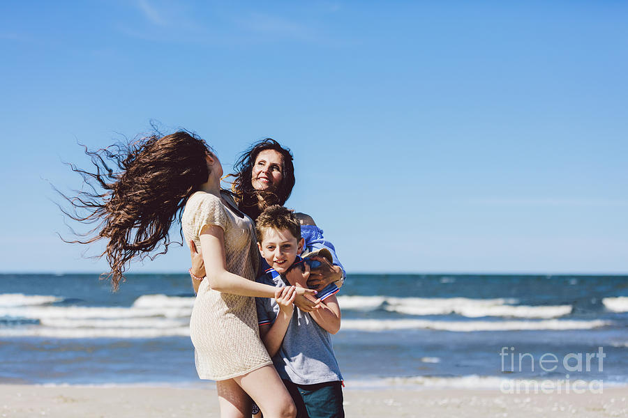 Summer Photograph - Mother and children hugging and standing on the beach by Michal Bednarek