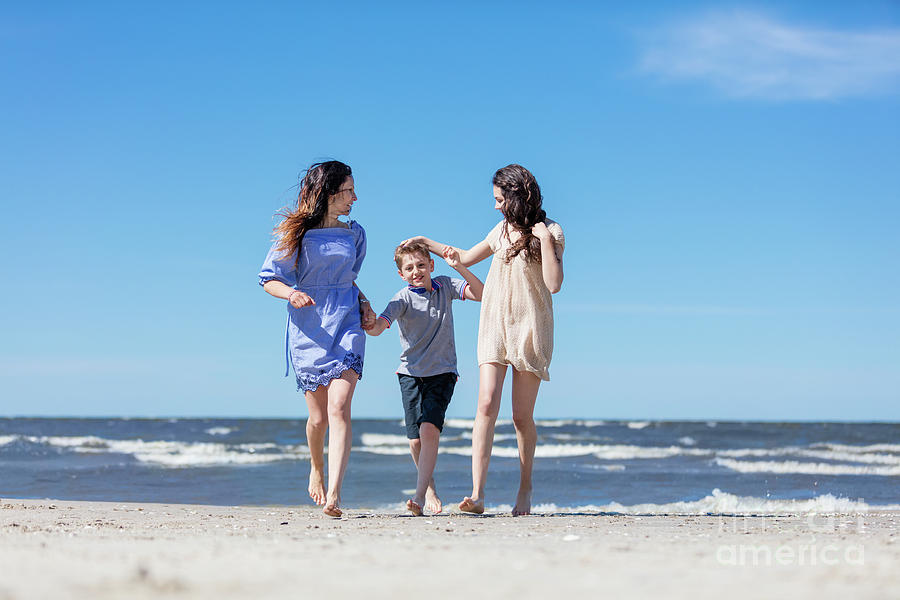 Mother and her children having a walk by the sea. Photograph by Michal Bednarek