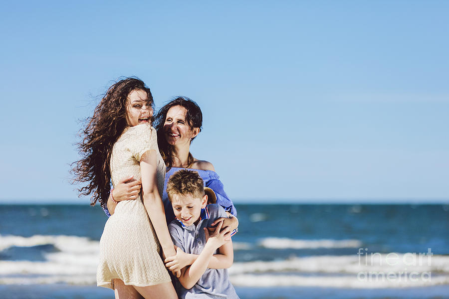 Mother, daughter and son hugging on the beach. Photograph by Michal Bednarek