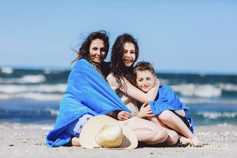 Mother, daughter and son sitting wrapped in a blanket. Photograph by Michal Bednarek