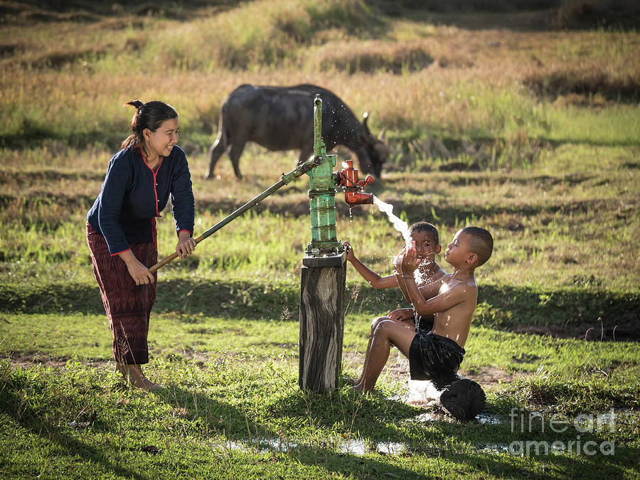Mother her sons shower outdoor from Groundwater pump. Photograph by Tosporn Preede
