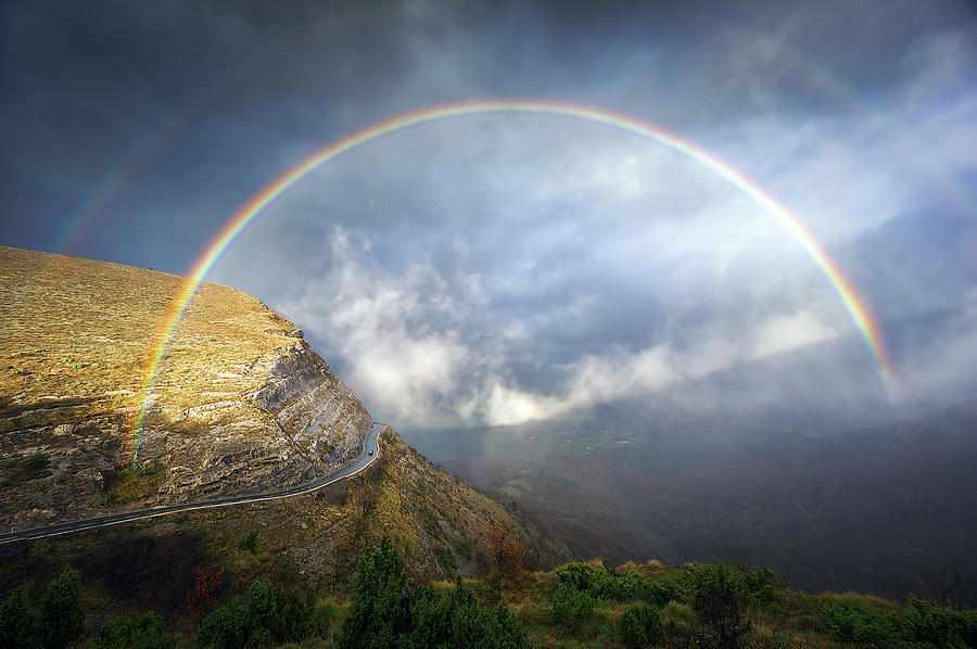 Mountain Pass Road With Stormy Clouds And Rainbow Photograph by Mikel Martinez de Osaba
