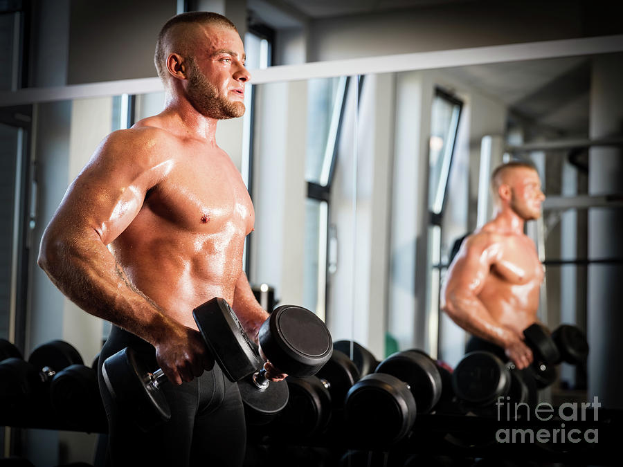 Muscular man working out at a gym. Photograph by Michal Bednarek
