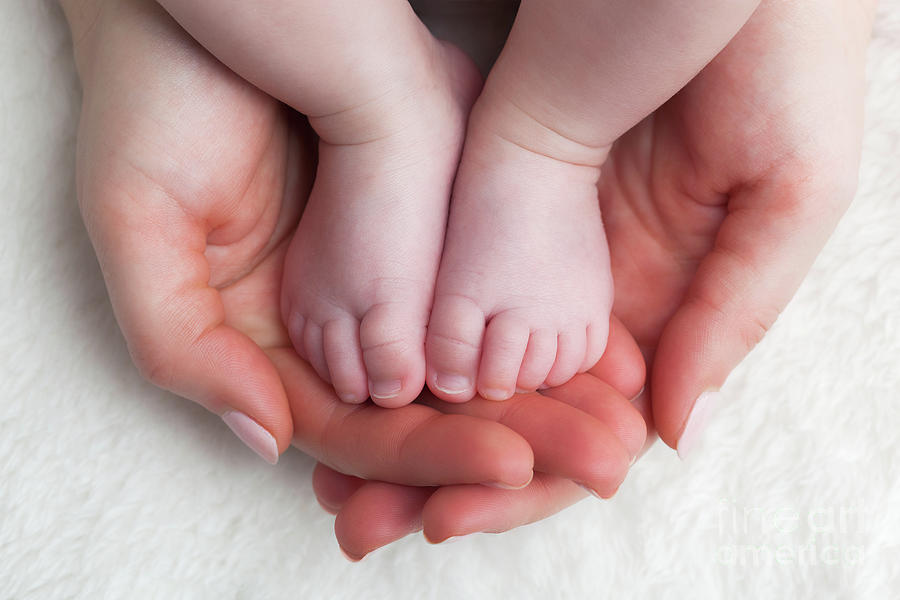 mom-holds-in-his-hands-a-small-baby-foots-small-legs-of-a-newborn-baby