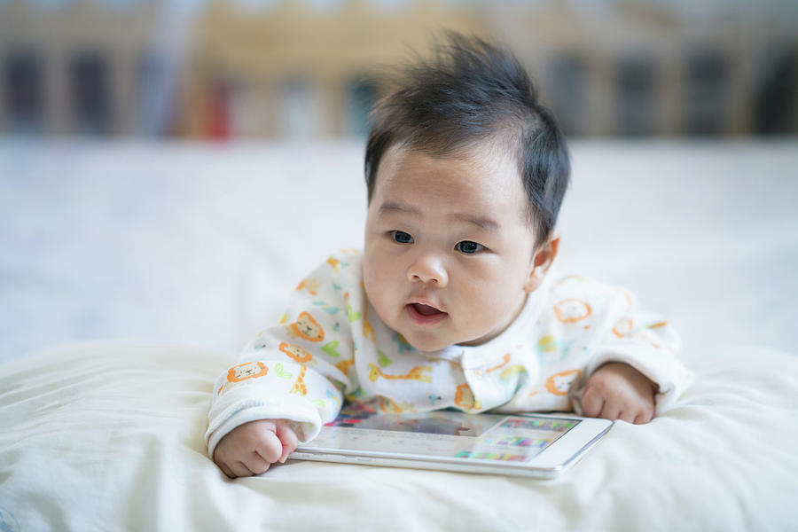 Newborn baby play smart phone on the bed Photograph by Anek Suwannaphoom