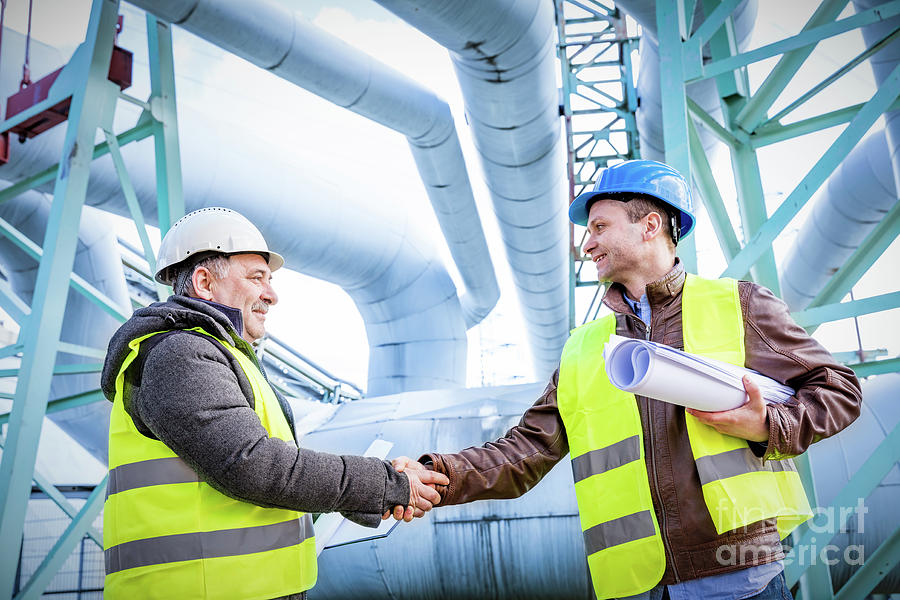 Oil refinery engineers successful deal handshake. Photograph by Michal Bednarek