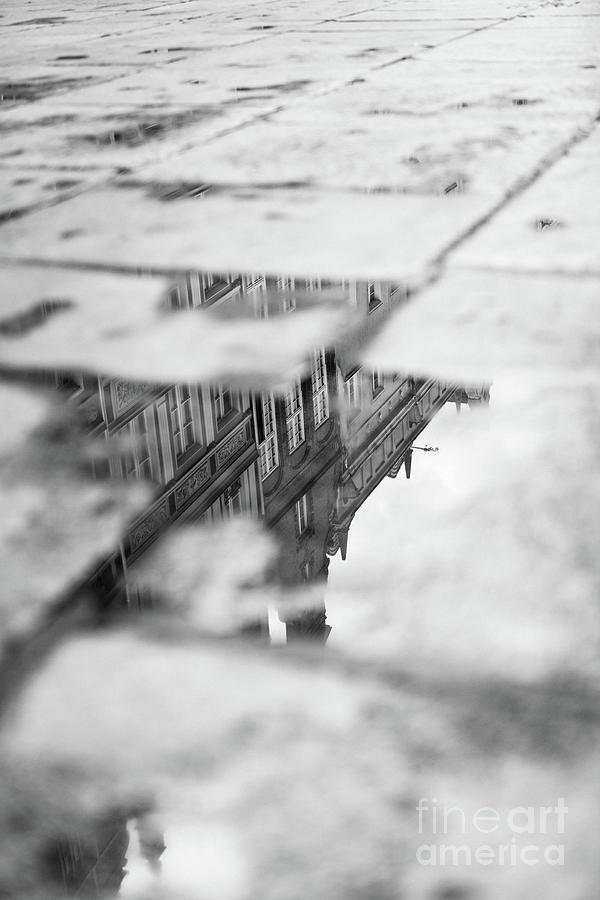 Old tenement buildings reflecting in a puddle. Photograph by Michal Bednarek