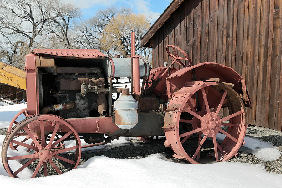 Old tractor against a barn wall Photograph by Jeff Swan