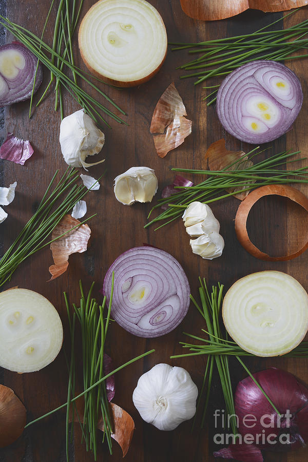Onions chives and garlic scattered on wood table Photograph by Milleflore Images