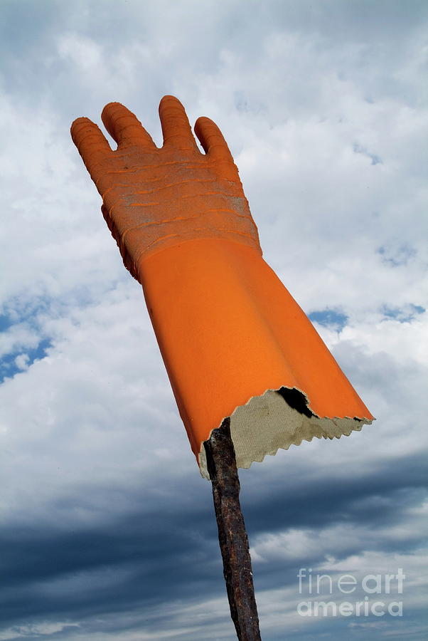 Orange rubber glove on a wooden post against a cloudy sky Photograph by Sami Sarkis