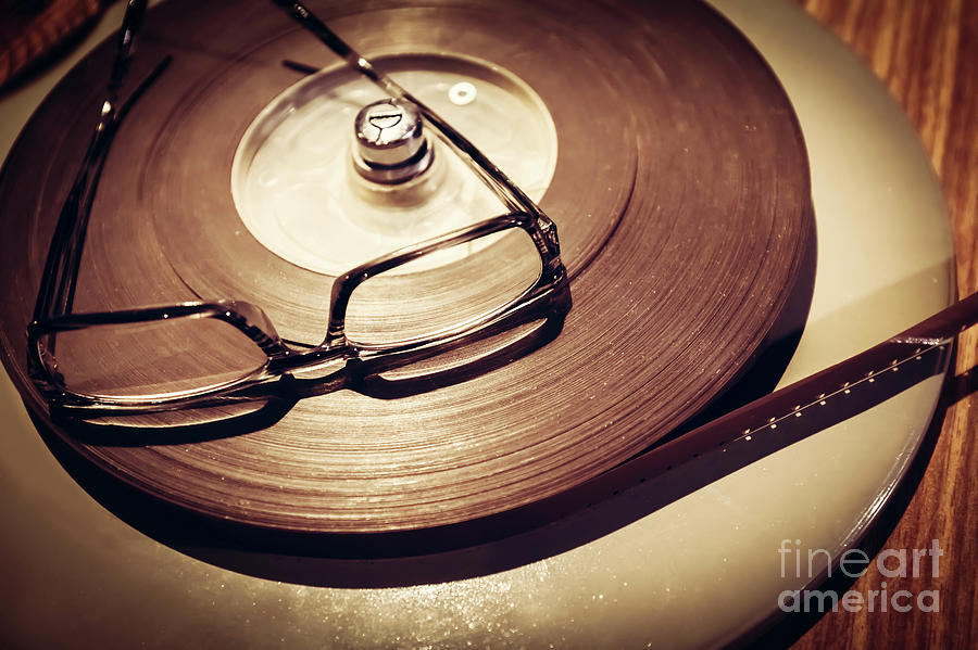 Vintage Photograph - Pair of glasses laying on the top of retro film reel. by Michal Bednarek