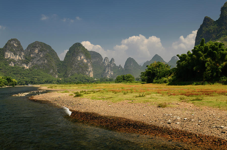 Pebble shore of the Lijiang River China with pointed Karst cones ...