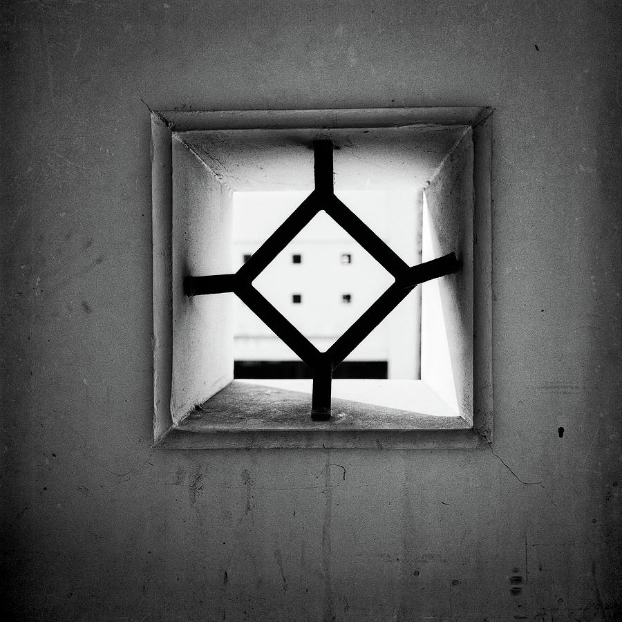 Black And White Photograph - Peep Hole in Parking Structure Wall by YoPedro
