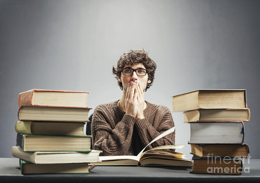 Pensive man sitting by the piles of books. Photograph by Michal Bednarek