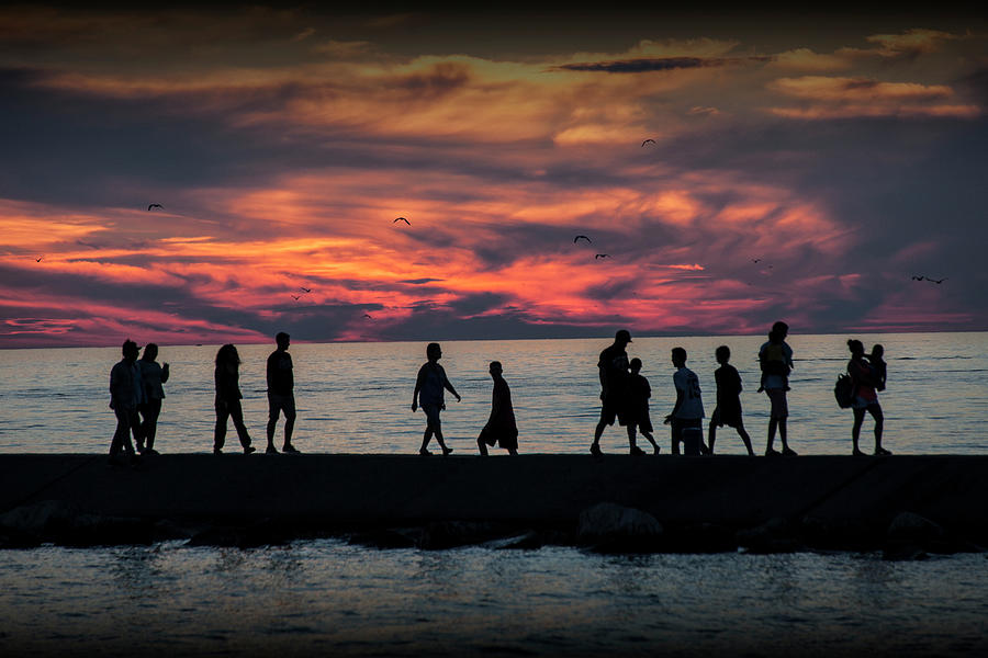 People walking on the Breakwater at Ottawa Beach at Sunset Photograph by Randall Nyhof