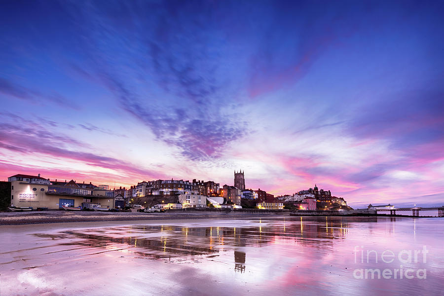 Pink sunset reflections over Cromer town at dusk Photograph by Simon Bratt