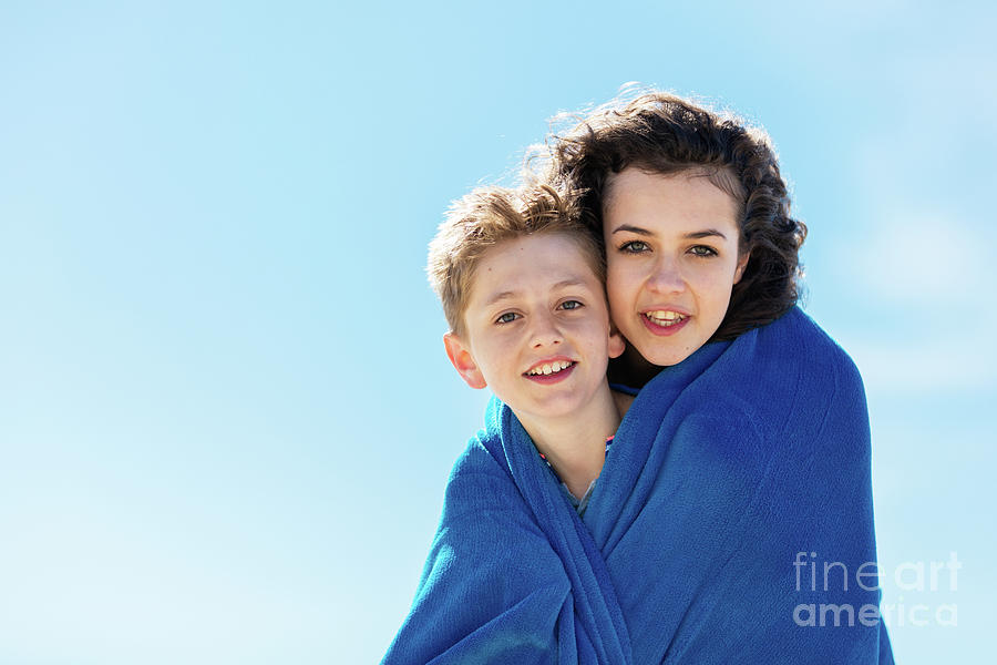 Portrait of brother and older sister covered in a blanket. Photograph by Michal Bednarek