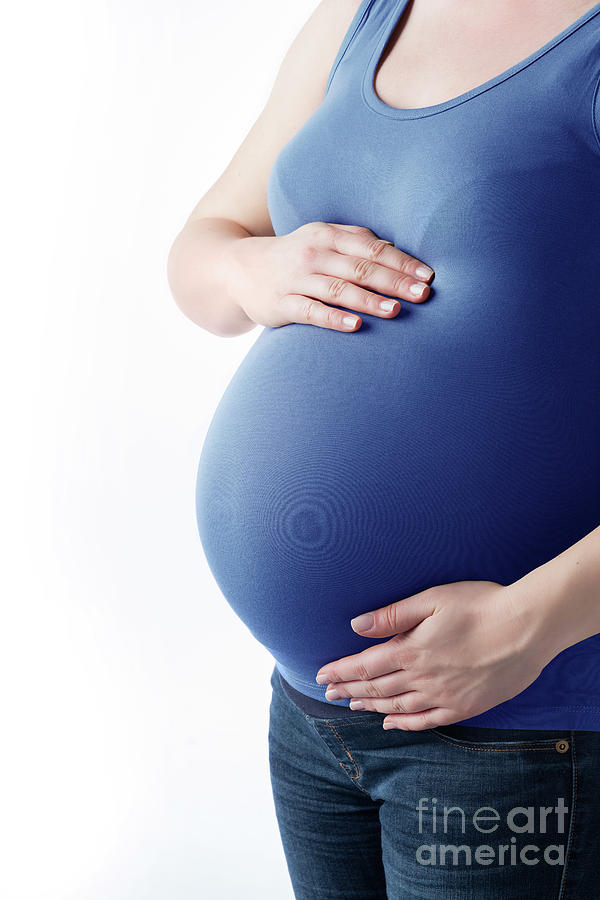Pregnant woman in casual clothes holding her belly. Photograph by Michal Bednarek
