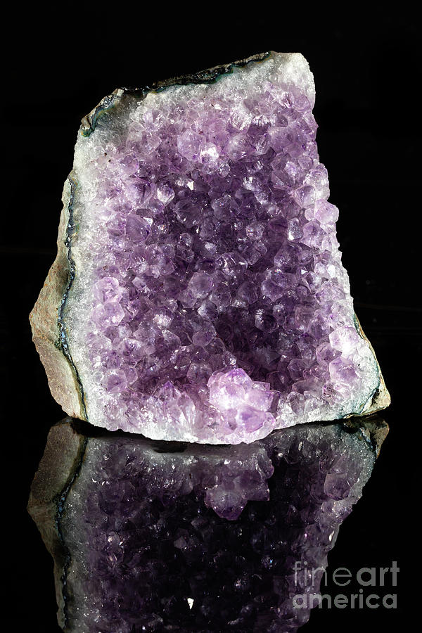Raw amethyst stone on a black reflective background. Photograph by Michal Bednarek