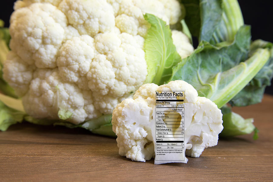 Raw cauliflower head and floret with nutritional fact label on w Photograph by Karen Foley