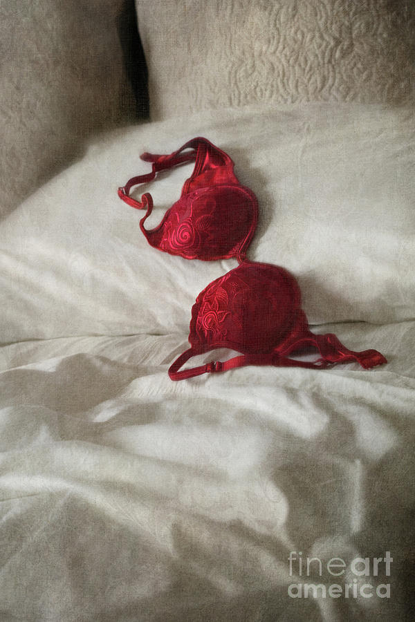 Red brassiere laying on bed by Sandra Cunningham