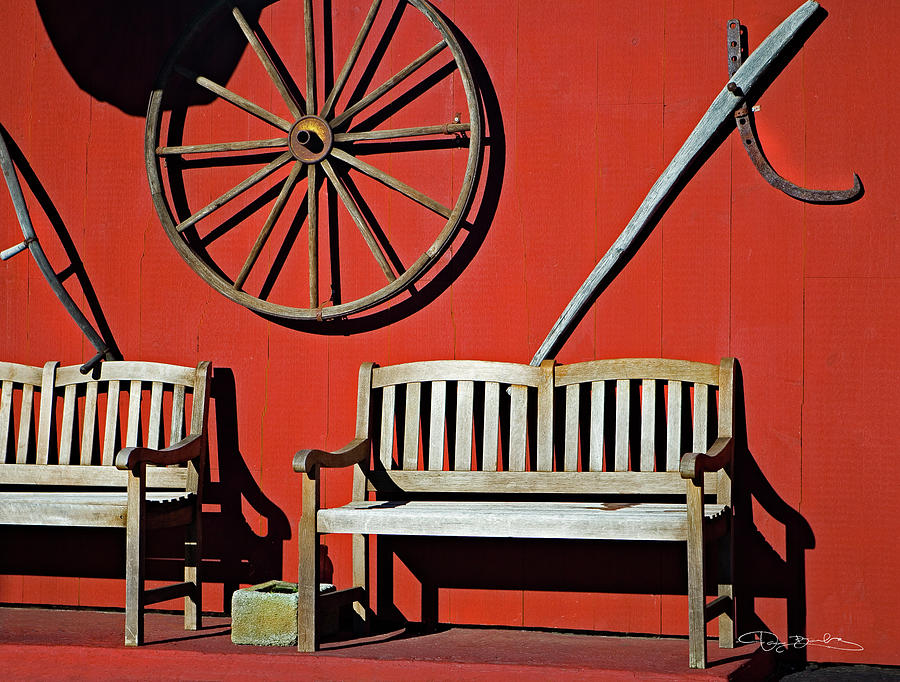 Red Wall With Benches And Wagon Wheel Photograph by Dan Barba