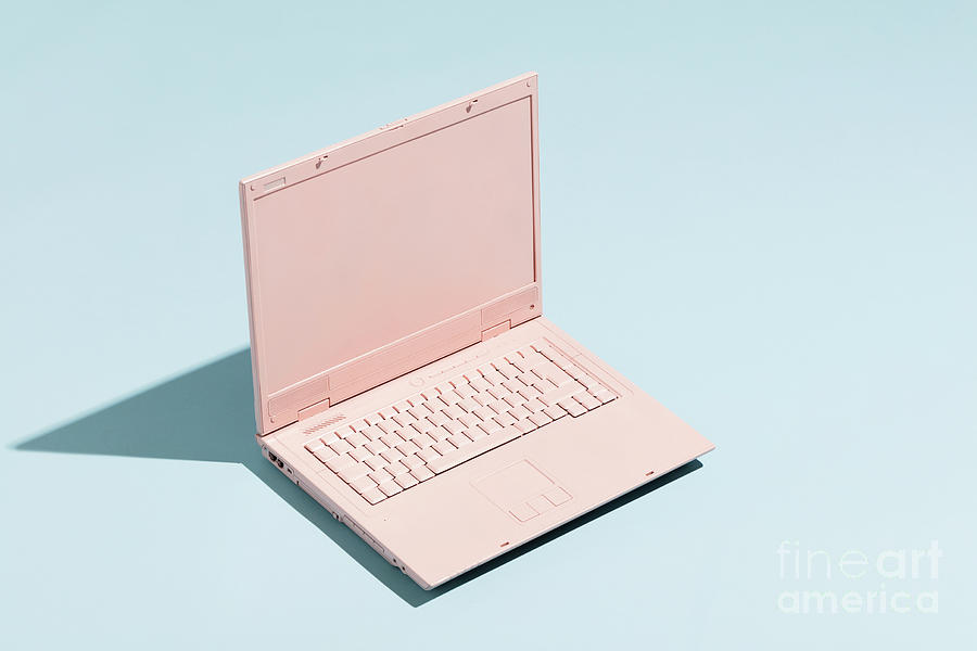 Retro pink laptop on a pastel blue background. Photograph by Michal Bednarek