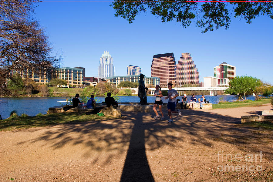 Musician Photograph - Runners jog past the Stevie Ray Vaughan Statue on Town Lake in Austin Texas by Dan Herron